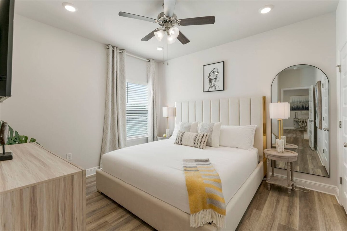 A relaxing retreat with windows for natural light, a ceiling fan, and bedside lamps.