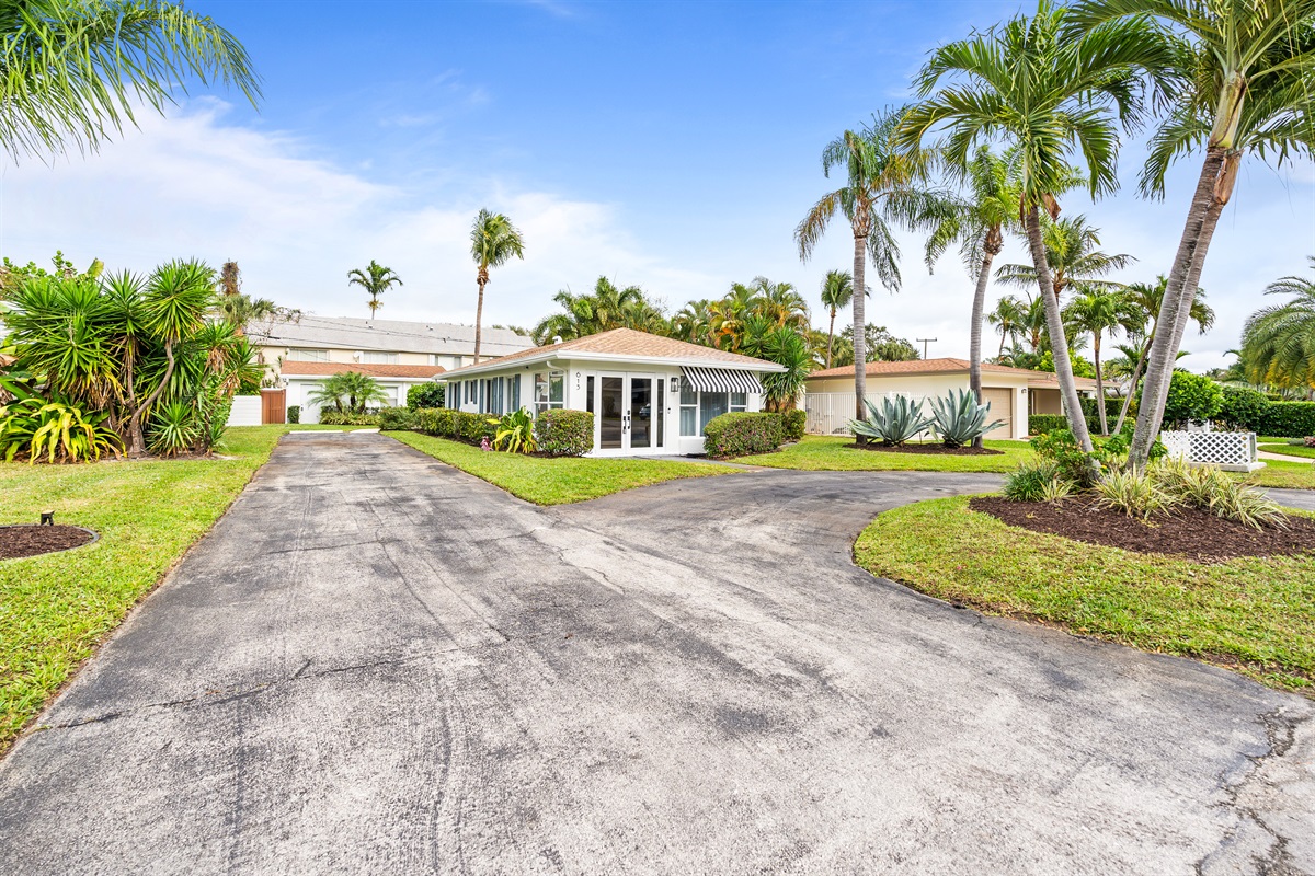 A sleek modern exterior framed by swaying palms and tropical landscaping.