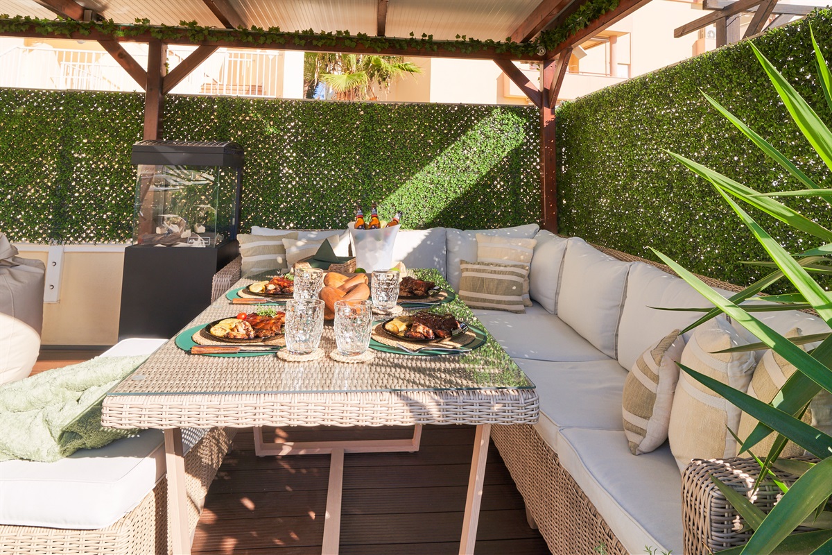 Relax beneath the covered pergola with cozy seating, fireplace, and dining area. Perfect for long evenings, romantic dinners, or movie nights on the outdoor TV under soft ambient lights.