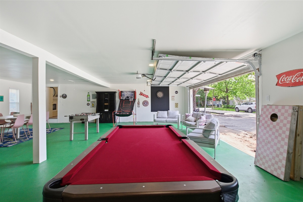 Pool Table close-up with open garage access and outdoor view. 1,000 sq ft Game Room with Pool Table, Foosball, Arcade Games, and Smart TVs included.