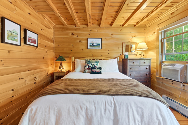 Rest comfortably in this inviting bedroom featuring warm wood interiors and peaceful surroundings.