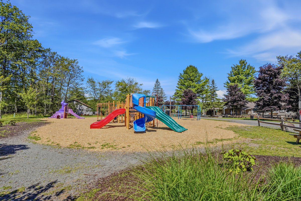 Community playground with colorful play structures on a sandy surface