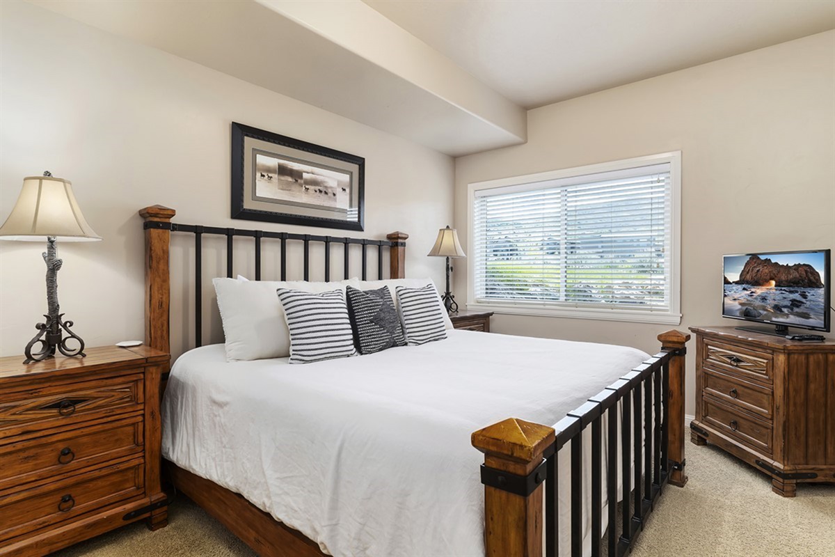 An inviting bedroom with a queen bed and a large window for fresh mountain air.
