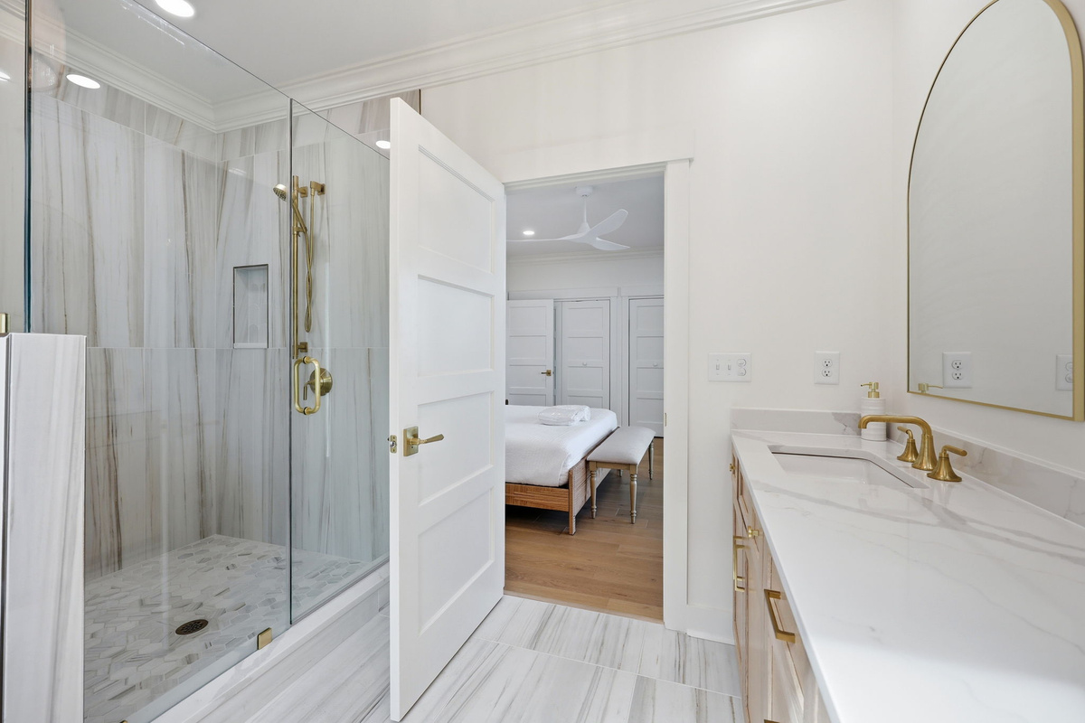 Bathroom with walk-in glass shower, gold fixtures, and en-suite connection to first-floor master bedroom