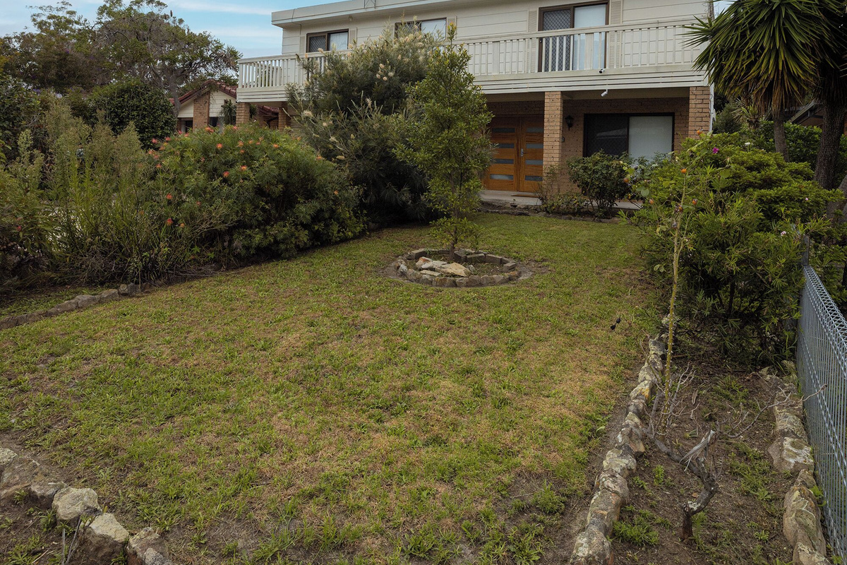 Established gardens, open lawn and balcony frontage give Luna’s Sanctuary a relaxed South Coast arrival feel.
