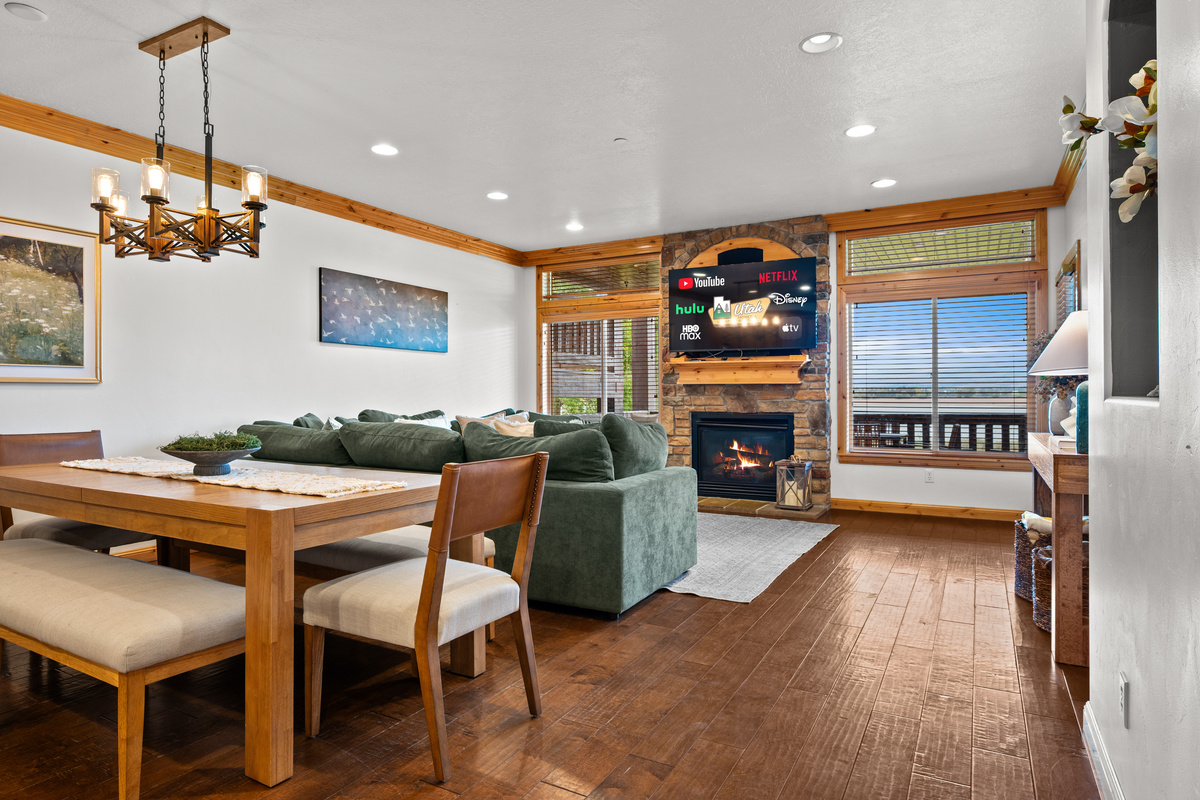Open-concept living and dining area with a cozy fireplace, lake views, large windows, and plenty of room to gather.