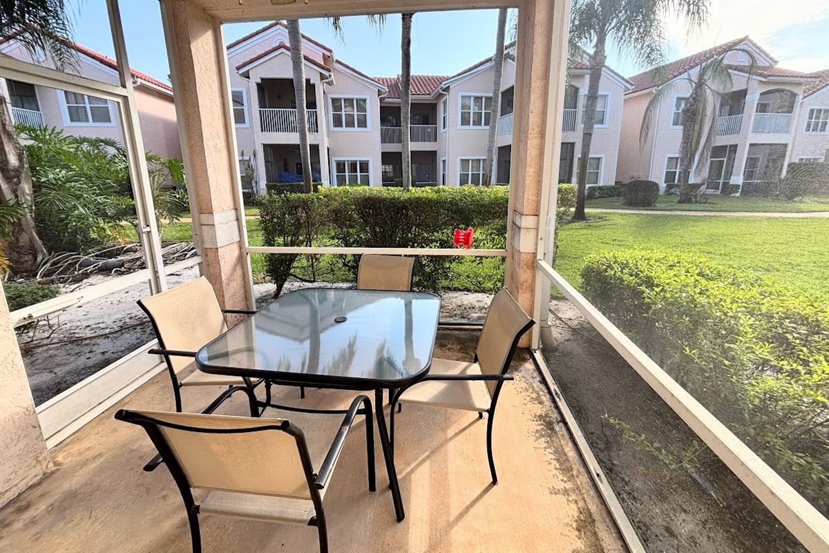 Private screened patio with outdoor dining space and peaceful views of the surrounding community grounds.