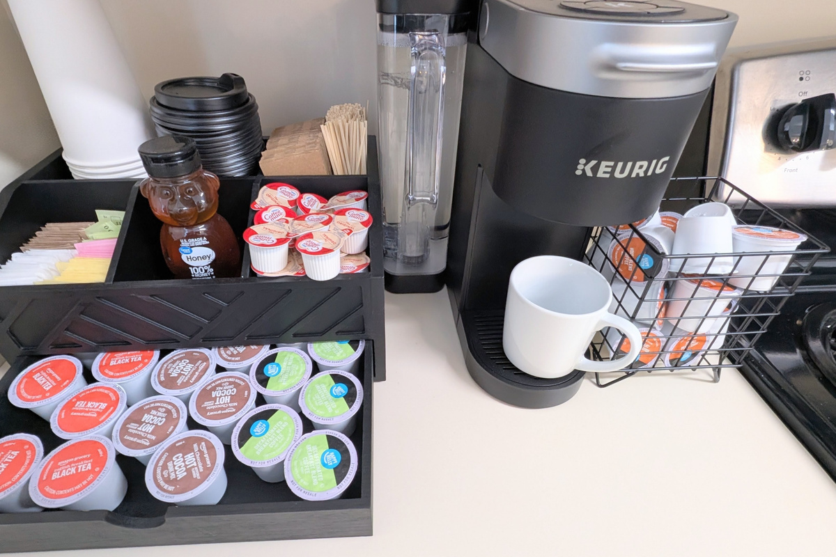 Start your day or wind down with a cozy drink from the stocked coffee bar, offering coffee, decaf, tea, and cocoa, along with mugs and to-go cups.