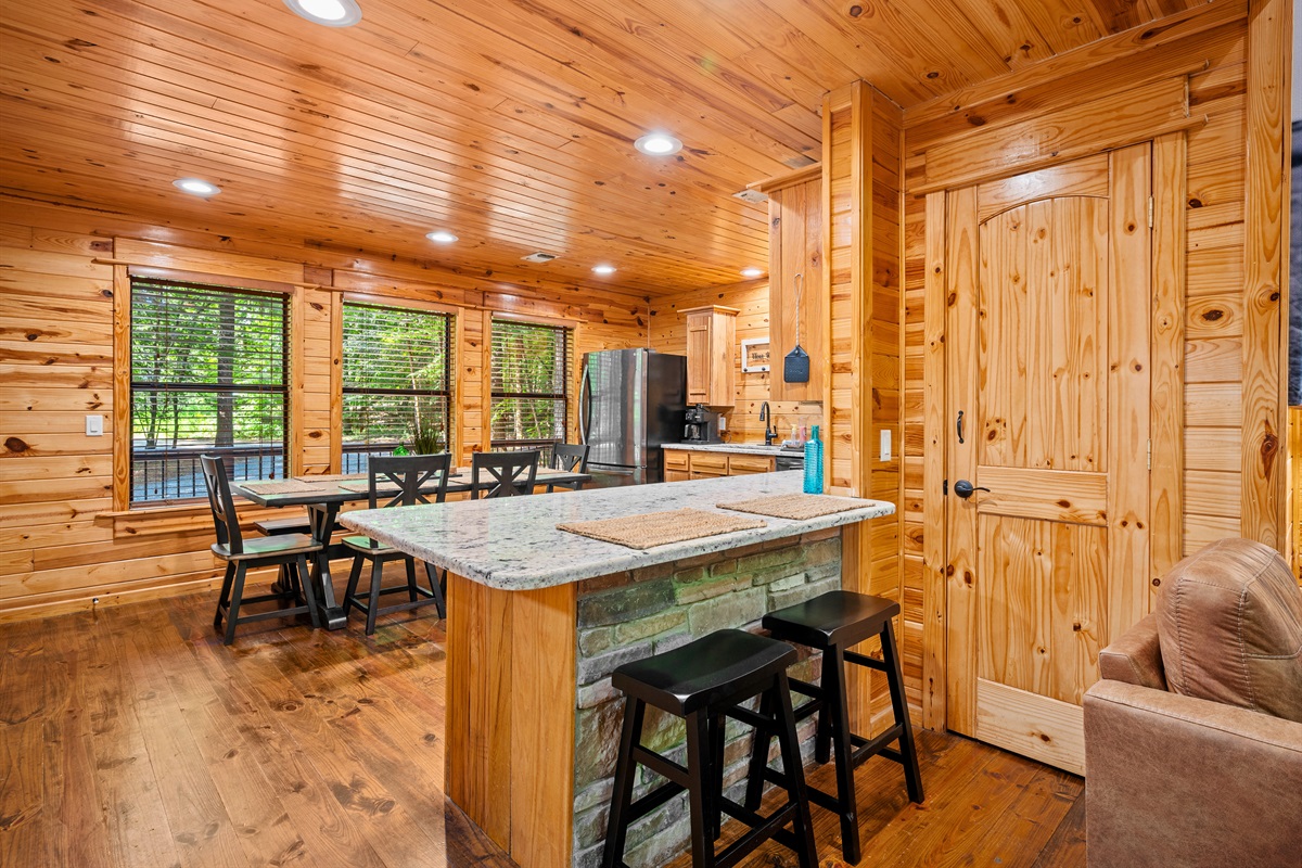 Kitchen island with granite top and bar seating, blending function and comfort in a wood-accented, open layout.