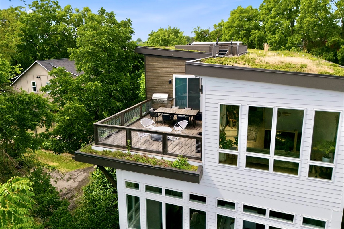 Rooftop terrace w/ lounge seating, green roof & panoramic treetop & skyline views all around.