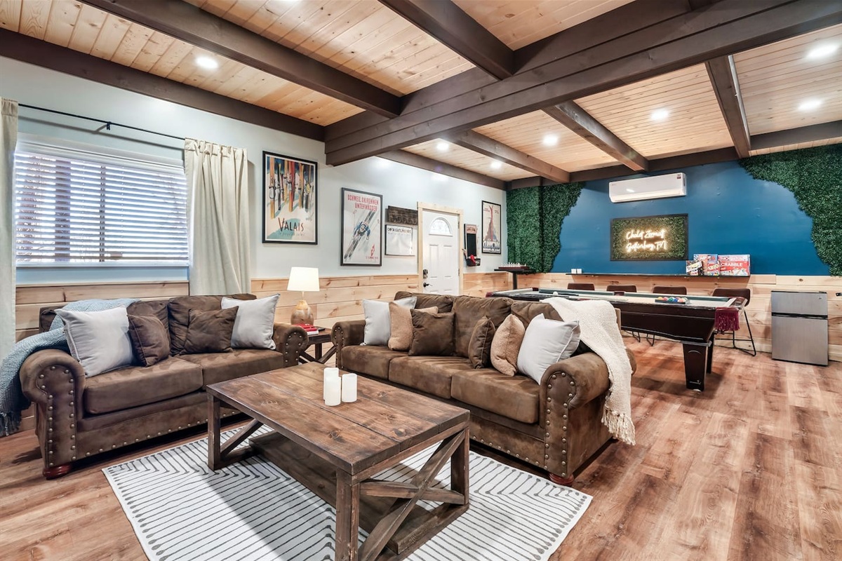 The lower level basement, with an exterior access door features 75" smart TV, pool table, ping-pong table topper, mini fridge, cornhole boards, 2 arcade games, a pull-out sofa bed, and a wood-burning fireplace. Plus a full bathroom on this level.