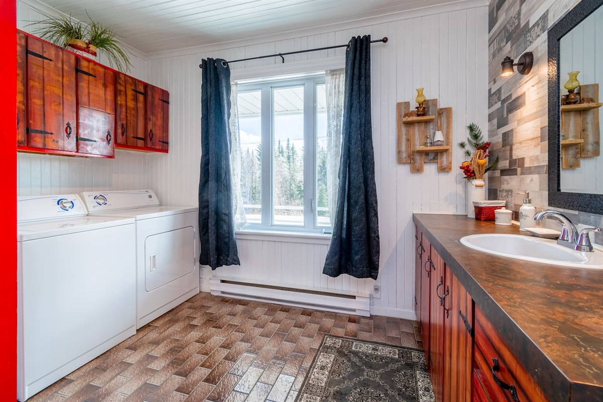Salle de bain complète avec un bain-douche, laveuse, sécheuse et lavabo. Elle est situé au rez-de-chaussée.