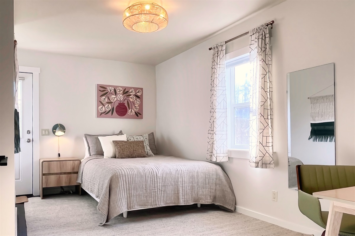 Peaceful second bedroom with Queen bed, writing desk, and window light — ideal for couples, solo guests, or kids.