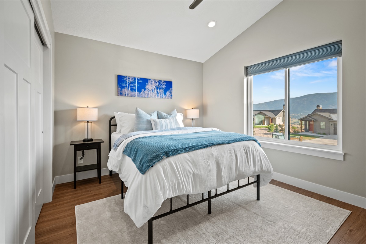 Beautifully appointed bedroom featuring stunning mountain views and a cooling ceiling fan for year-round comfort.