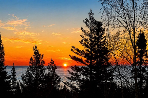 Wake up slowly at Treetops and step out onto the deck with a warm cup of coffee in your hand as the sun begins to rise over Lake Superior. The first light peeks through the trees, glowing softly between the branches before spilling out across the water.
