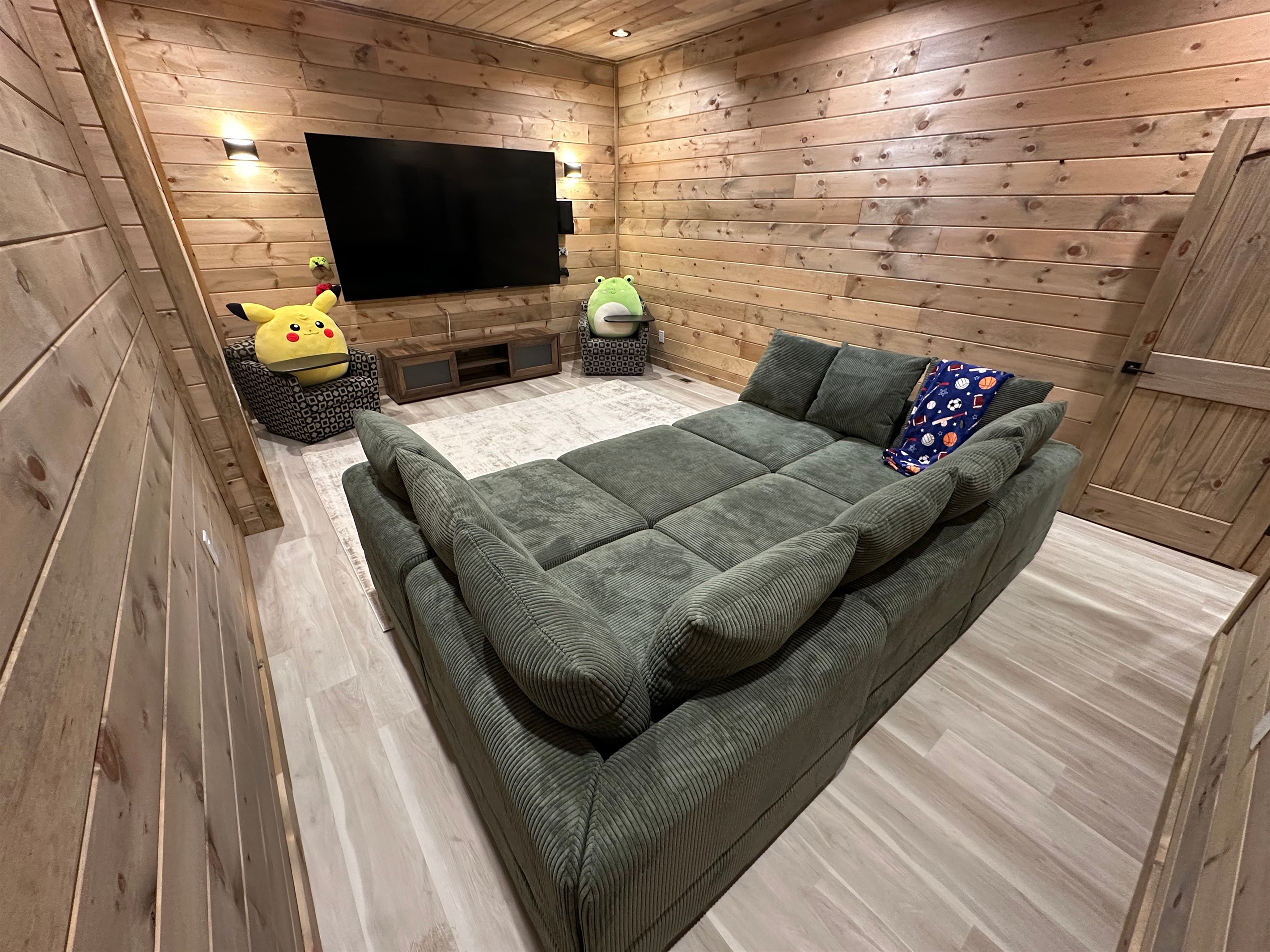 A cozy hangout made for movie nights and downtime. Plush seating, warm wood walls, and a big screen create the perfect spot for kids to unwind or for late night lounging after a full day outdoors.