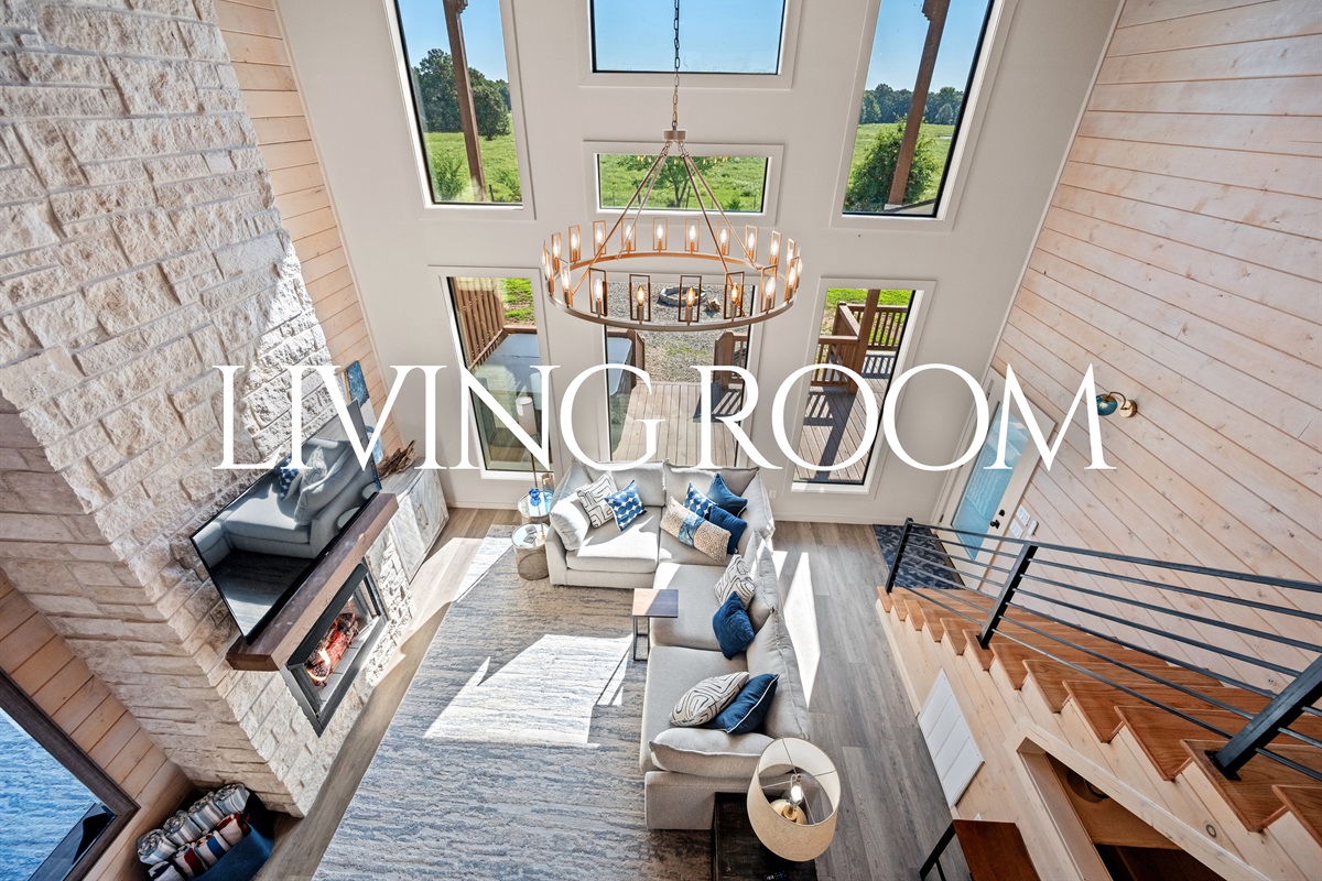 Living room with soaring ceilings, fireplace, and plenty of natural light.