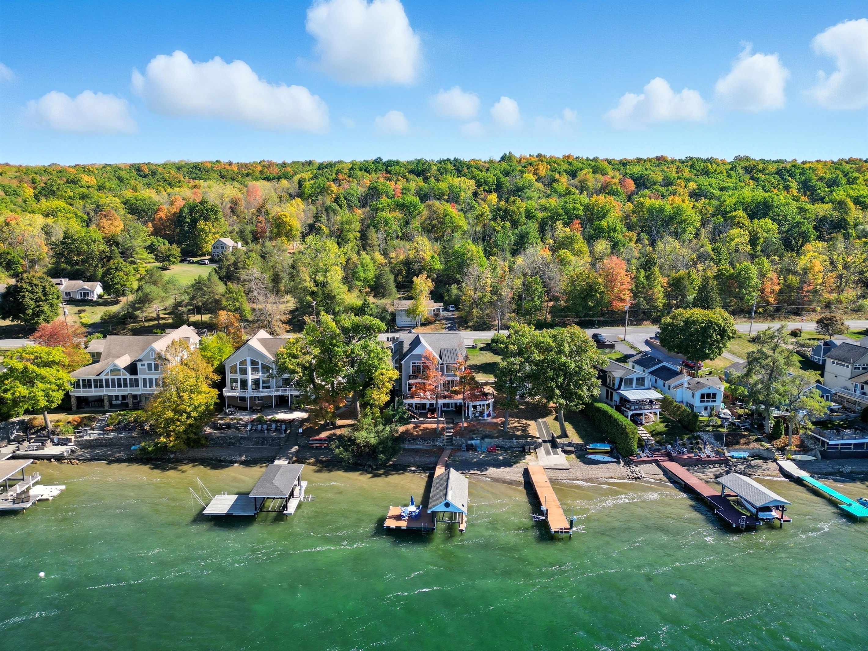 Drone view of lakeside neighborhood and colorful fall foliage.