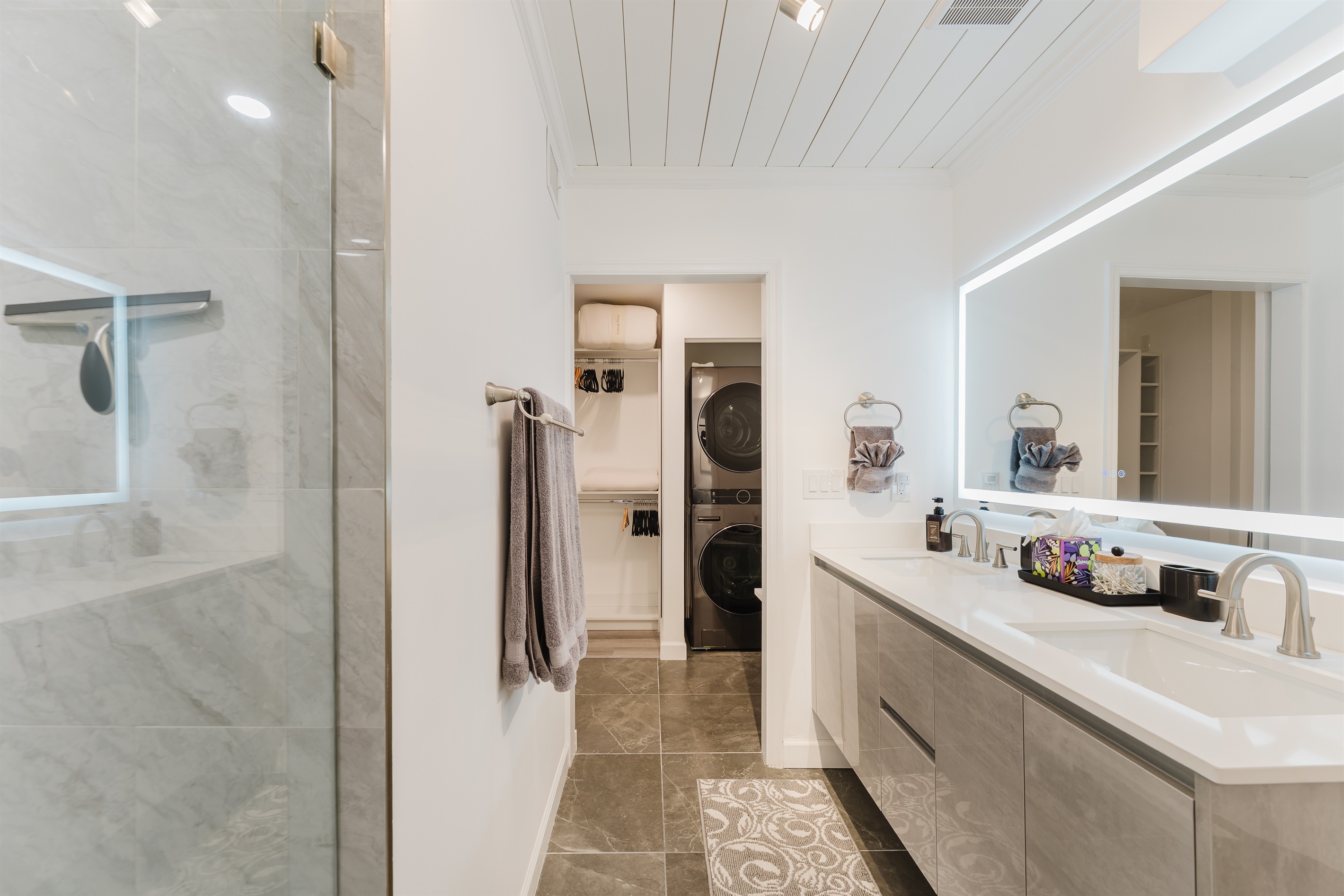 Spacious primary bathroom with double vanity, LED-lit mirror, and modern walk-in glass shower