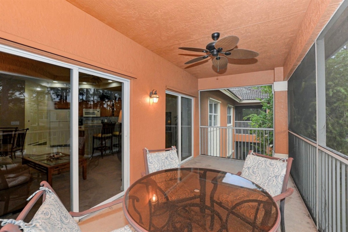 Private screened balcony with outdoor seating, ceiling fan, and covered space for relaxing outdoors.