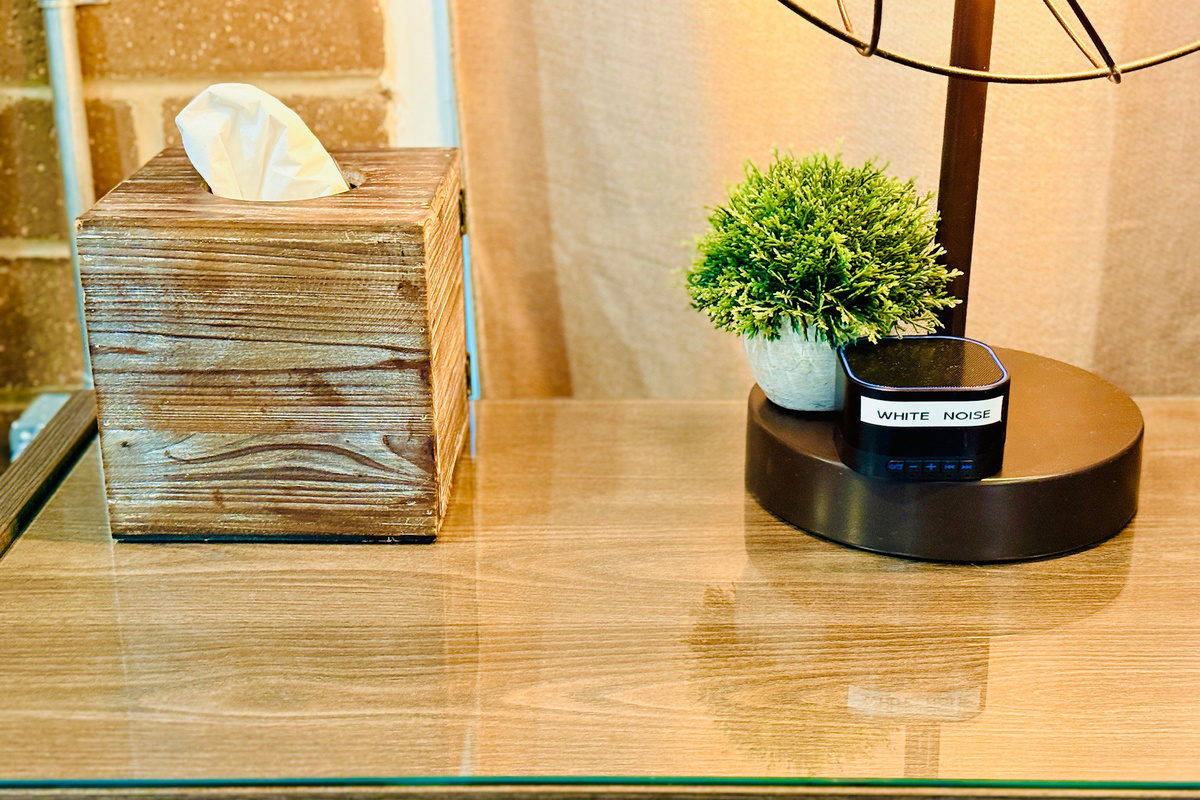 White-noise machine and tissues are provided beside the bed.