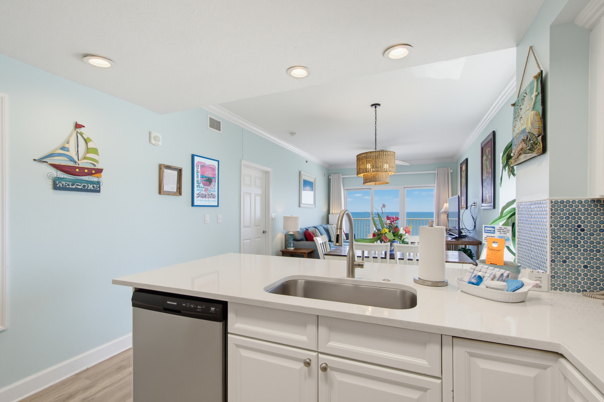 Kitchen sink and breakfast bar overlooking the dining area and living room with a TV.