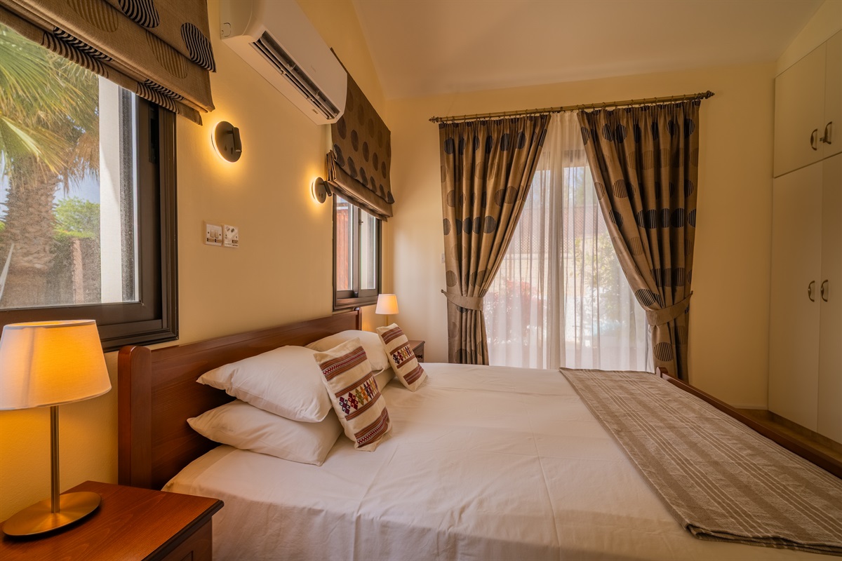 First king bedroom with direct patio access. King size bed, ceiling fan, dedicated AC/heating unit, vanity, large built-in wardrobes, bluetooth speaker/alarm clock.