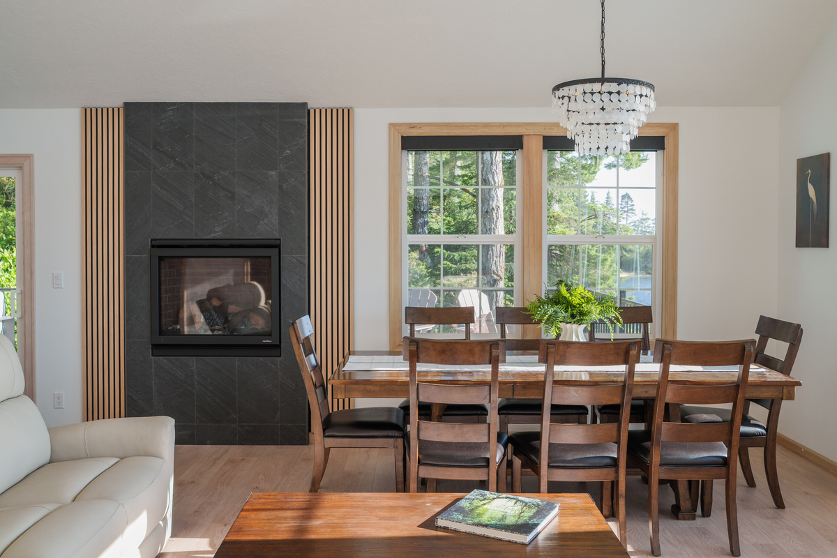 Gather around the spacious dining table for eight, where the cozy gas fireplace and sunlit lake views create the perfect setting for memorable meals and relaxed evenings together.