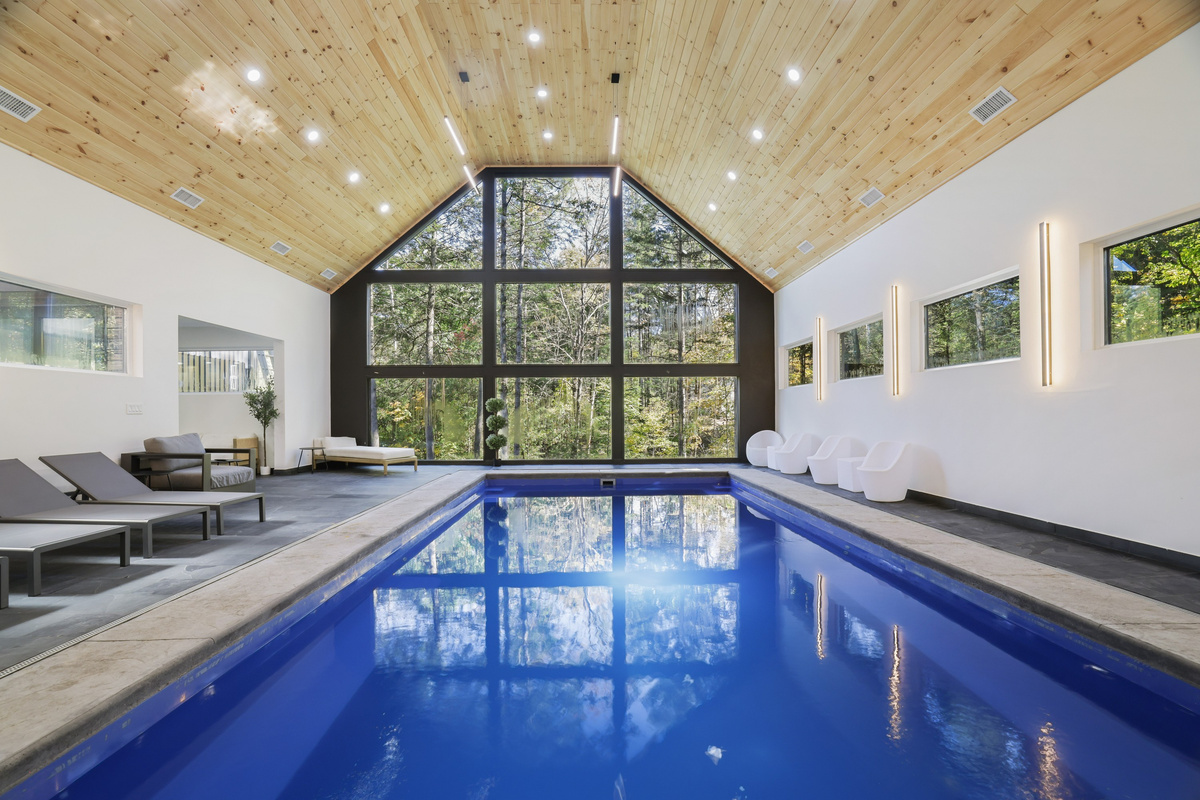 Swim beneath a soaring A-frame wall of glass, the forest just beyond the heated indoor pool