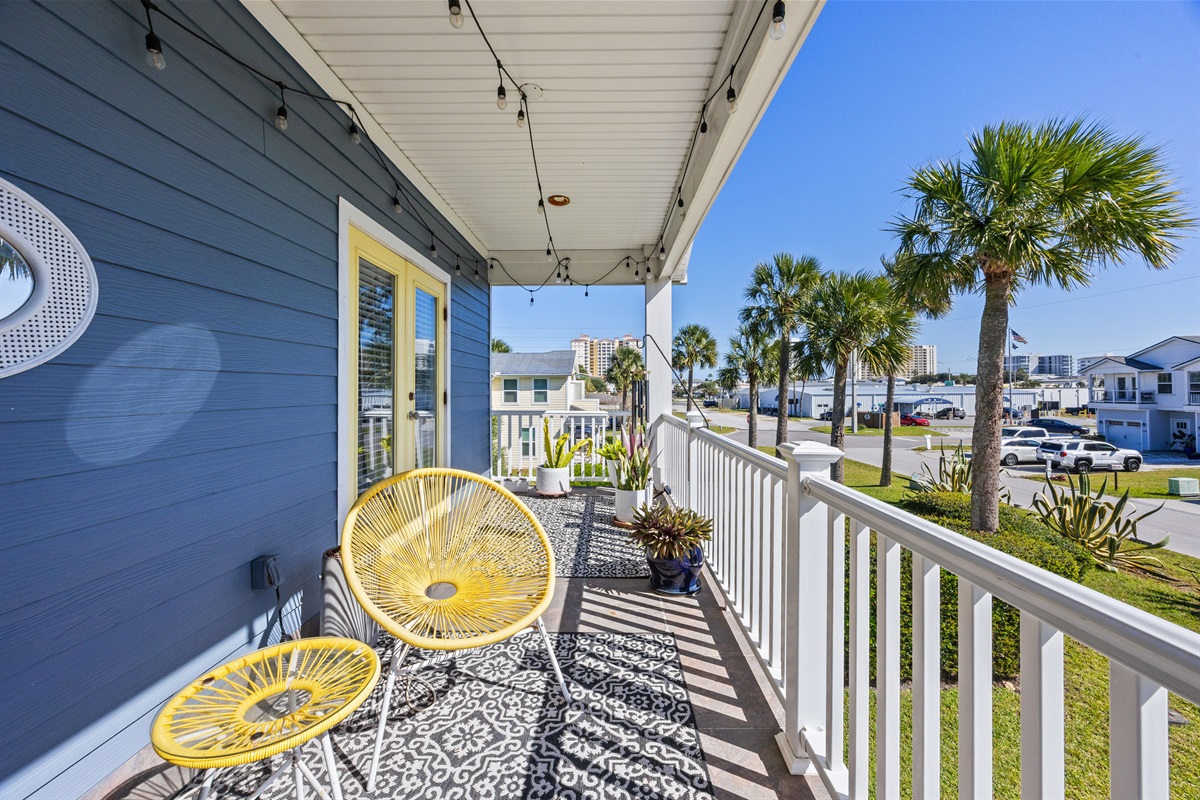Second‑floor balcony with yellow chairs and palm‑tree views in Jacksonville Beach rental home near the ocean.