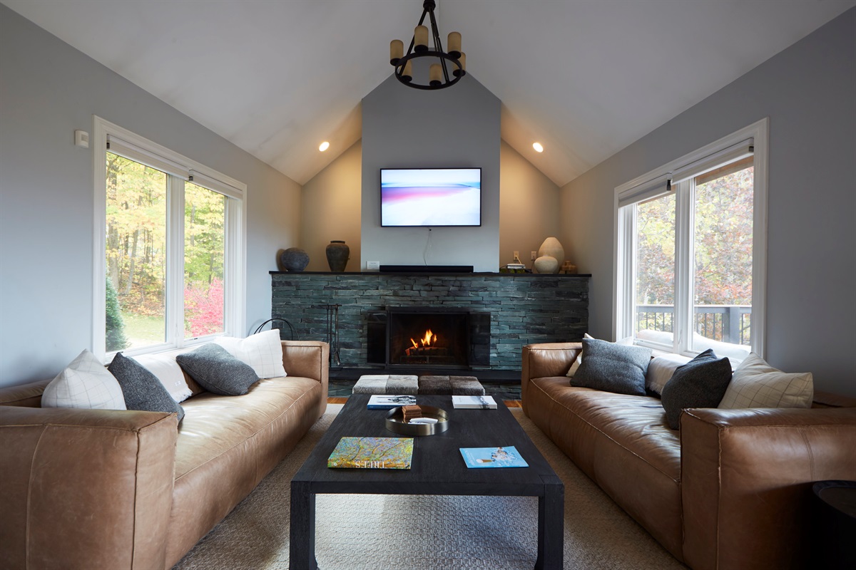 Gather around the grand stone fireplace in the main living room, boasting vaulted ceilings and stunning nature views right from the sofa.