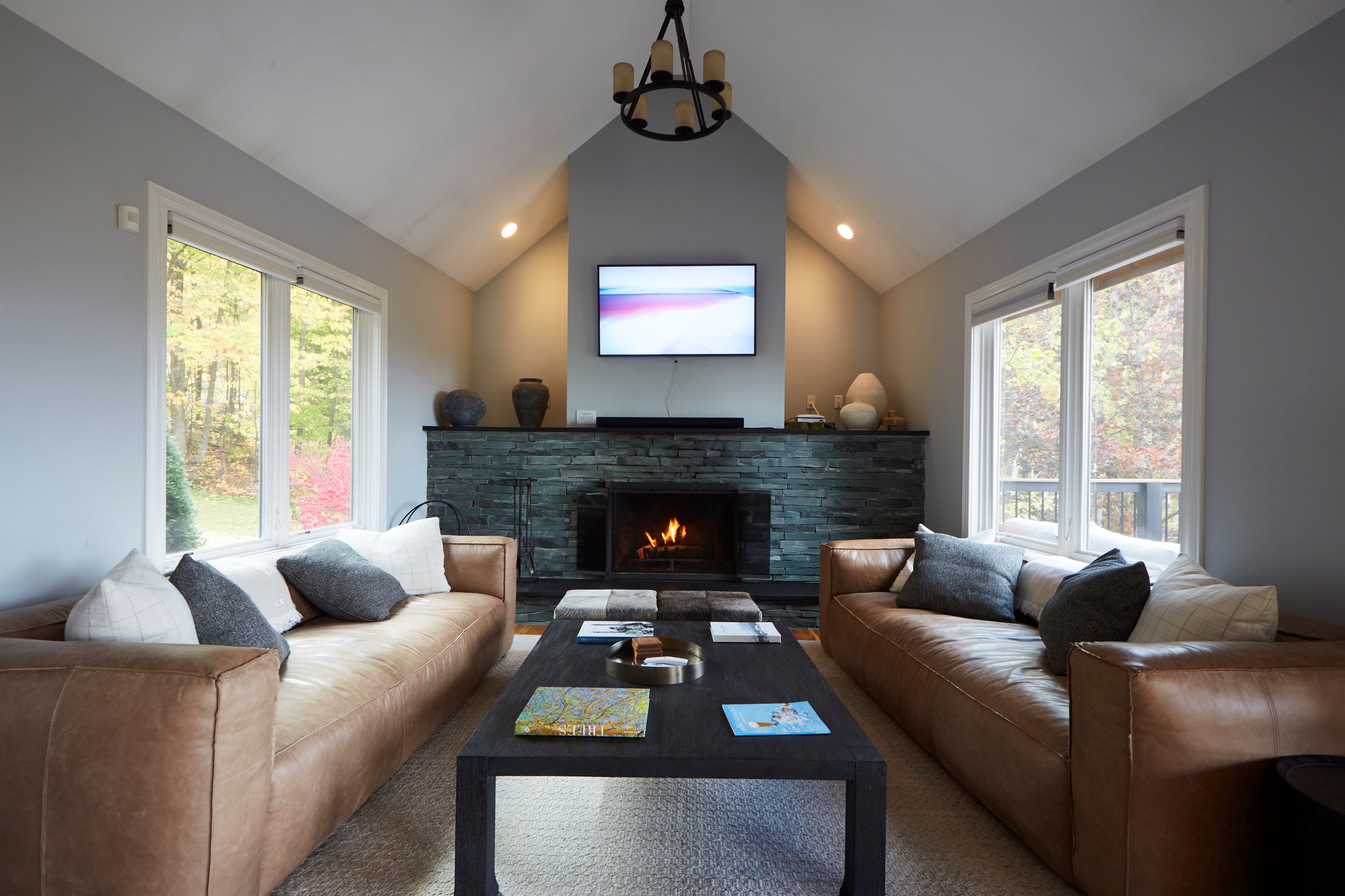 Gather around the grand stone fireplace in the main living room, boasting vaulted ceilings and stunning nature views right from the sofa.