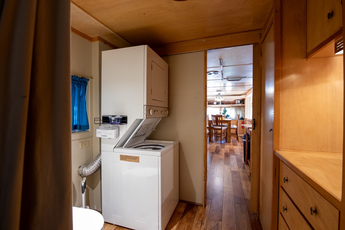 Beyond the vanity and tub/shower combo are the toilet and stacked washer/dryer