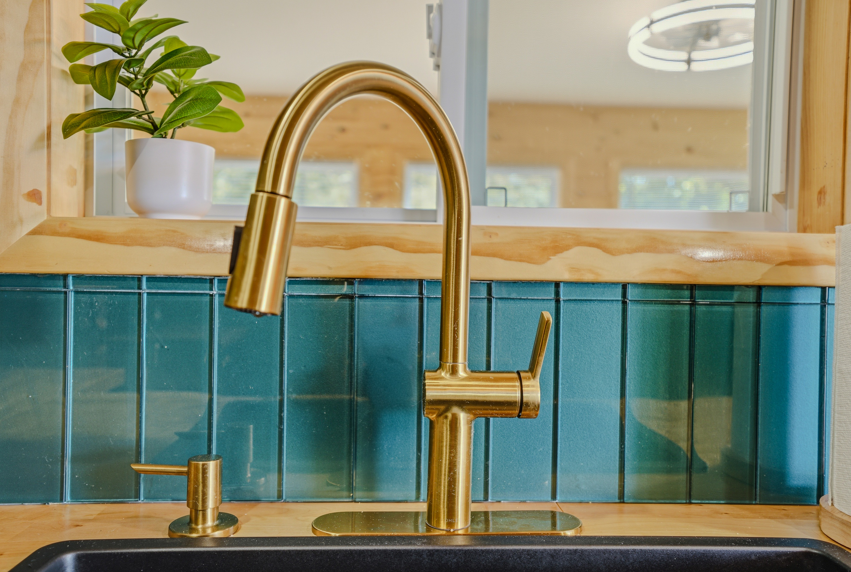 Kitchen detail — brass faucet, black undermount sink, and teal cabinetry up close