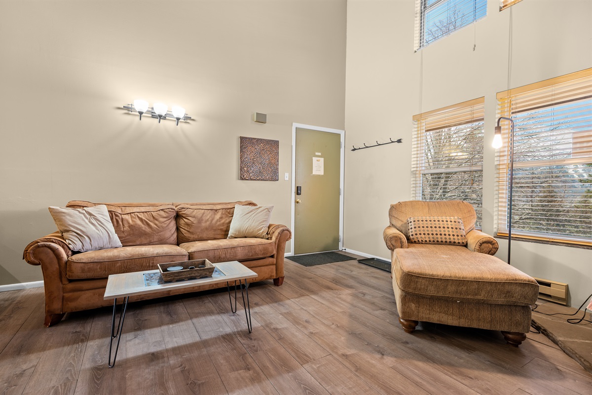 Spacious living area with cozy furnishings and large windows bringing in natural light.