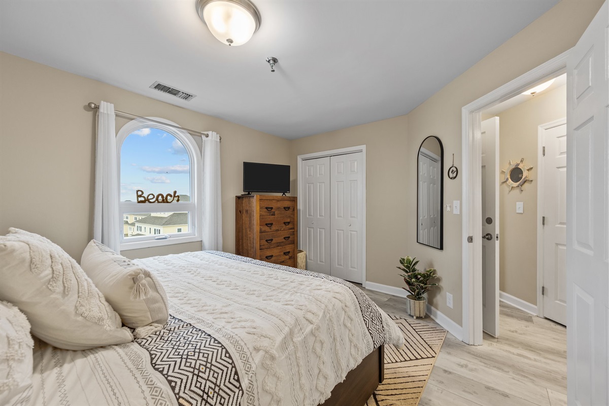 Retreat to the comfortable master suite featuring soft bedding, a large dresser, and plenty of natural light