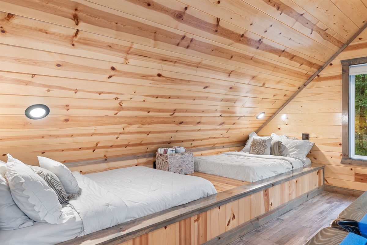 Cozy loft sleeping area tucked beneath warm wood ceilings