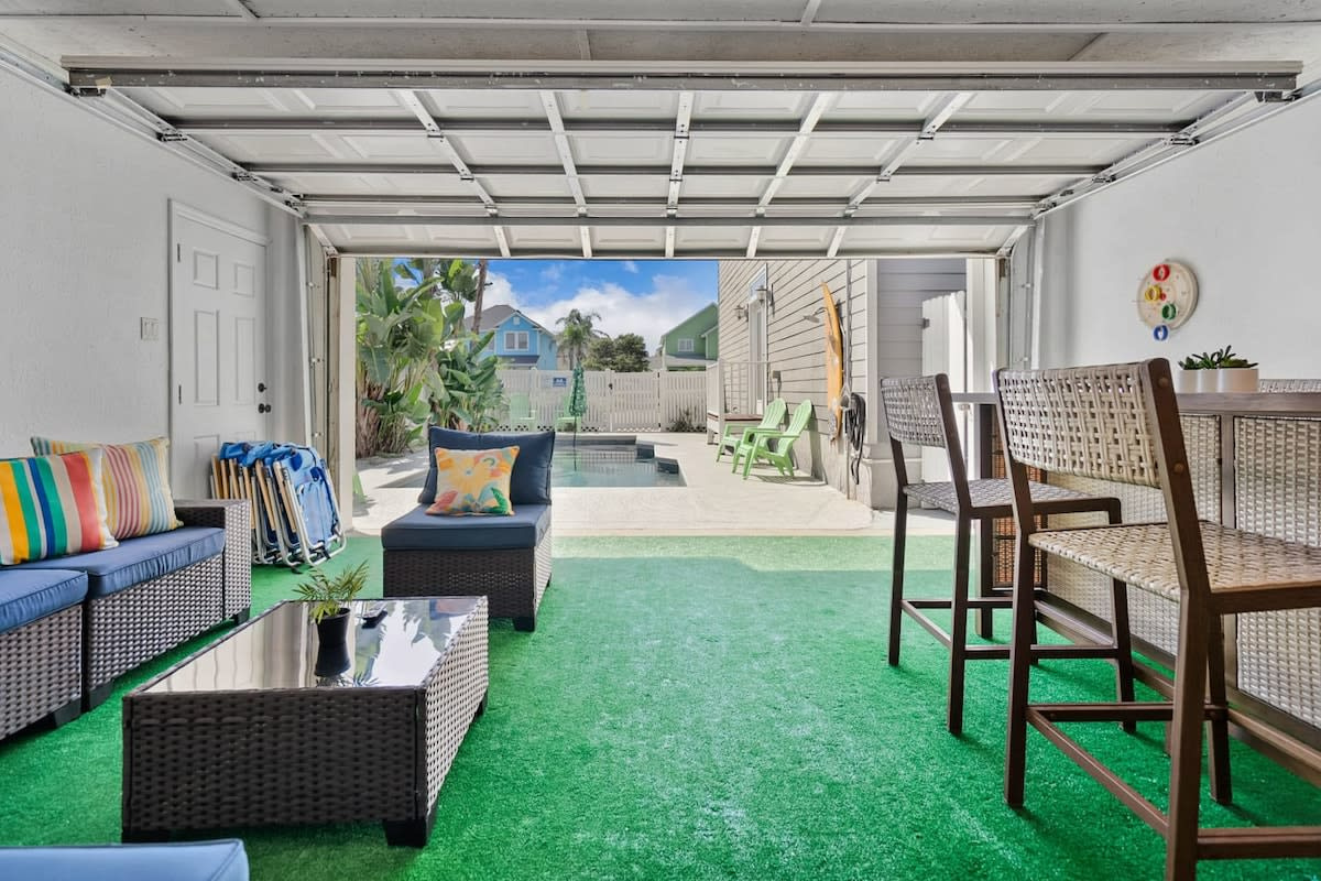 With the garage door up, the lounge and the pool deck become one enormous room. Somebody in the water, somebody at the bar, somebody refusing to move from the sofa. That is the shape of a good day here.