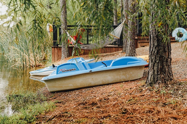 A charming view of the cabin’s lakeside amenities, including paddle boats and a hammock tucked between the trees. The Cove offers everything needed for a fun-filled lakeside retreat.