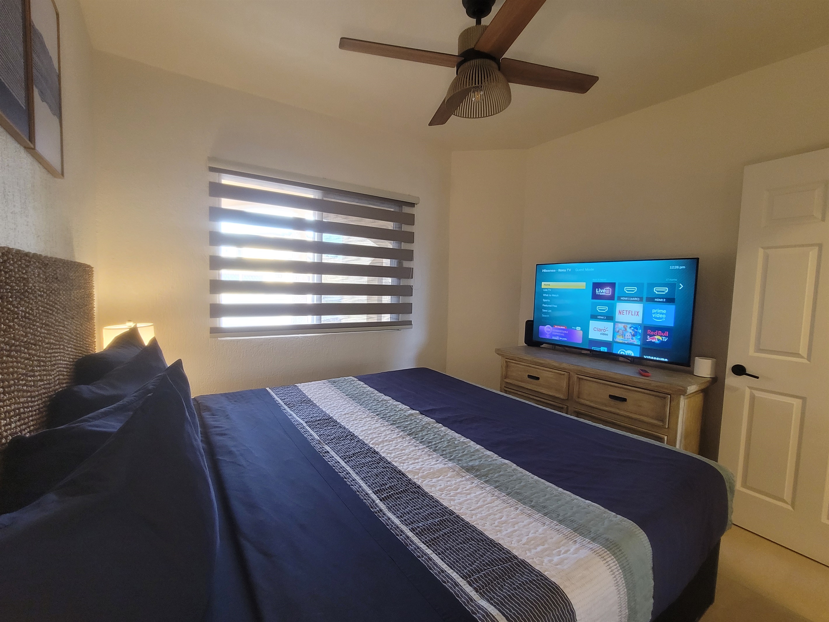 Guest bedroom featuring a king bed, two nightstands, lamps, dresser, closet and a Roku TV.