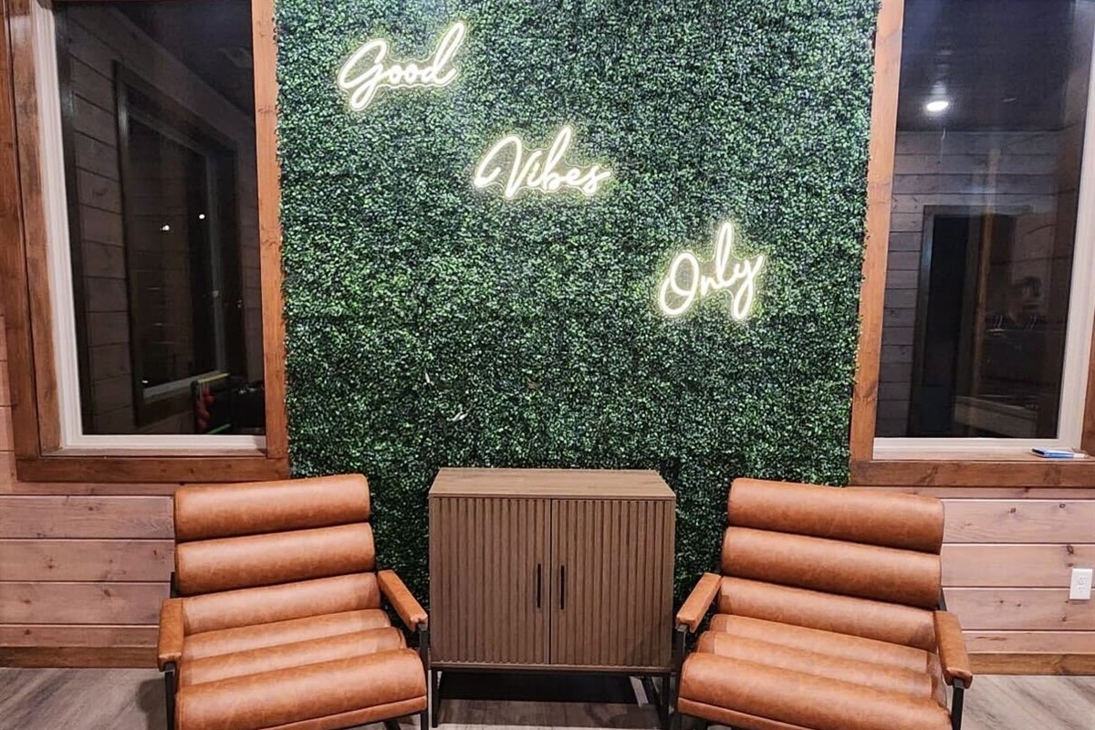 Fun corner with “Good Vibes Only” neon sign and chairs