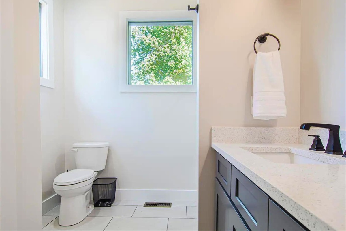 The bathroom’s modern design is both functional and elegant, with ample counter space and stylish fixtures.