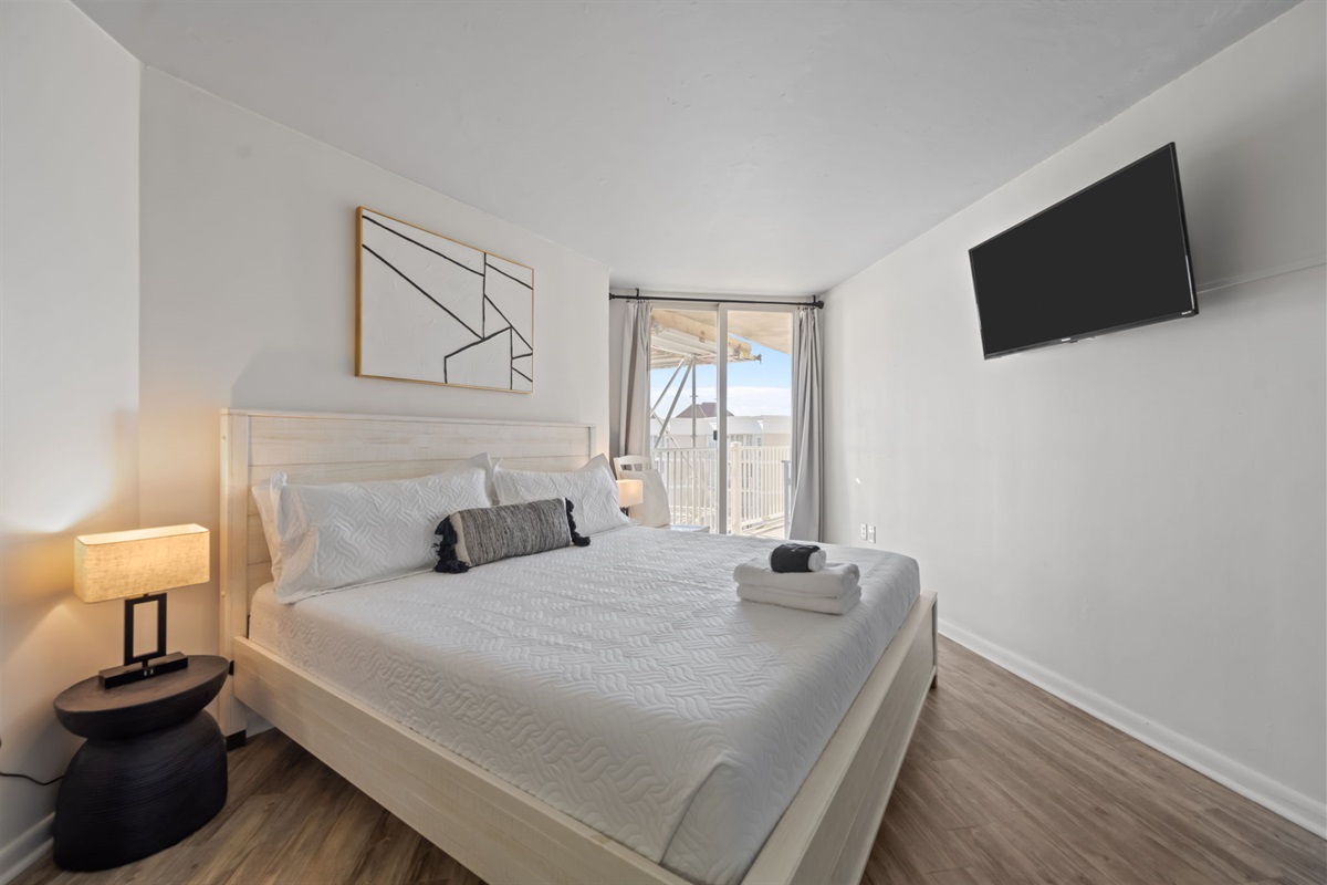 Bright King bedroom with quality linens, smart TV, and balcony sunshine