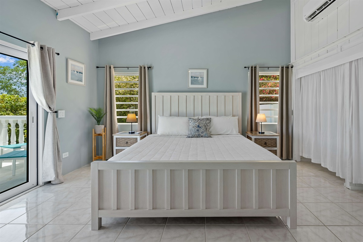 Primary bedroom with a king bed, private balcony, and ensuite bathroom