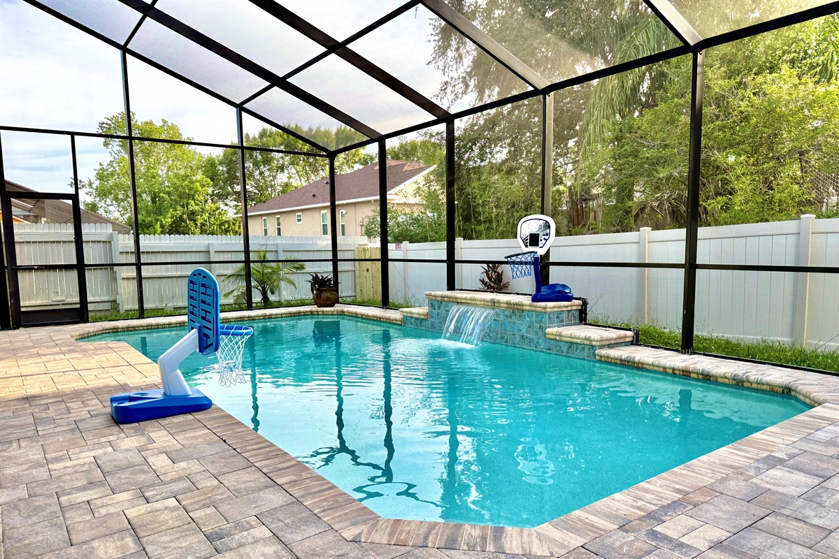 This screened-in backyard retreat features a sparkling private pool with a tranquil waterfall feature, perfect for cooling off after a day of Florida sunshine.