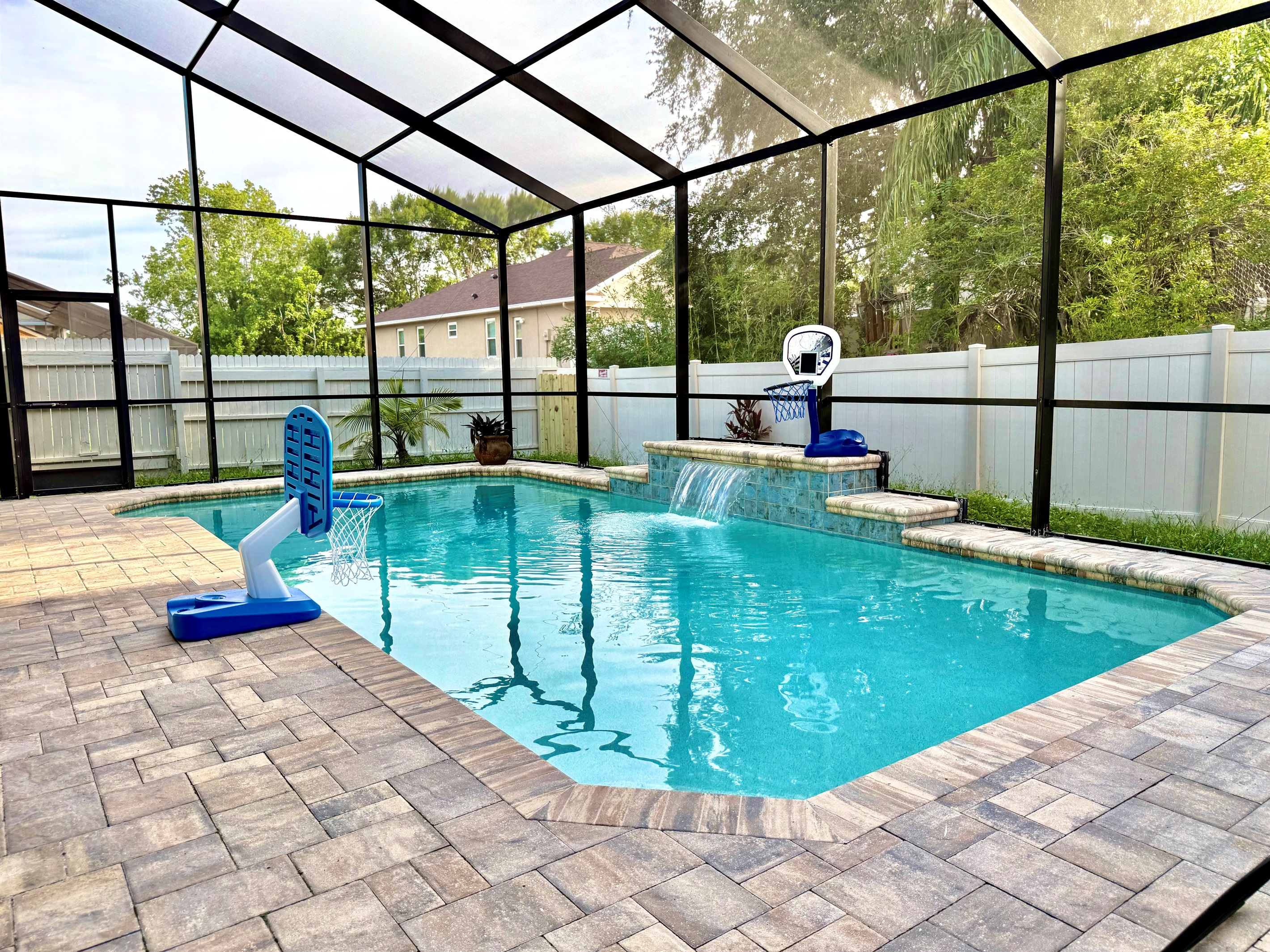 This screened-in backyard retreat features a sparkling private pool with a tranquil waterfall feature, perfect for cooling off after a day of Florida sunshine.