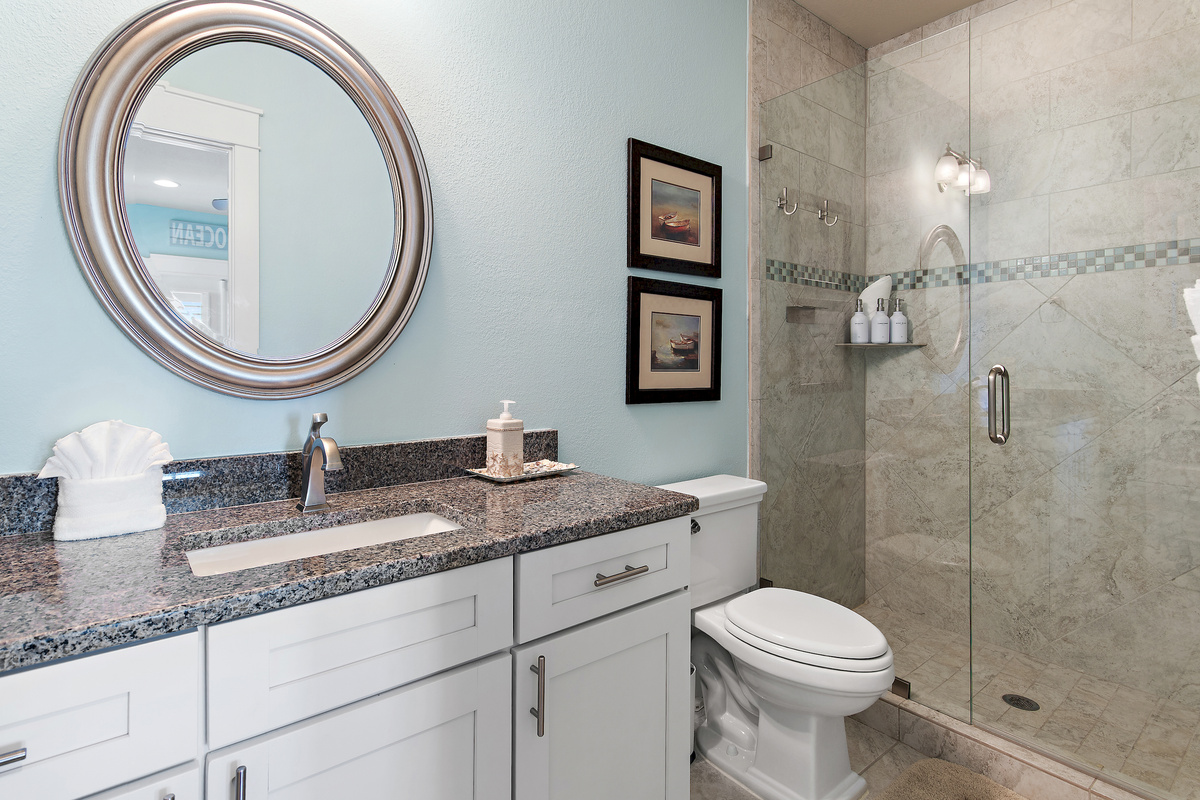 Bright, spacious bathroom with a walk in shower, generous vanity, and elegant coastal details.

