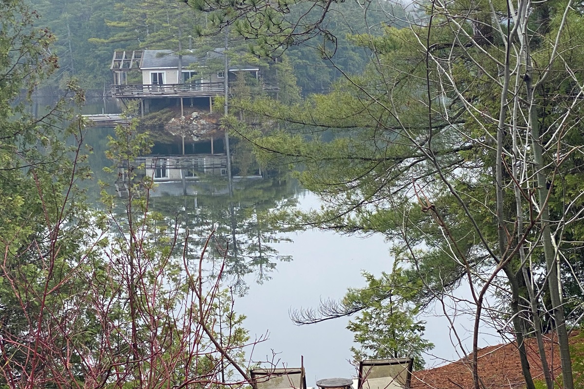 View of a calm lake in spring-time from side of cottage