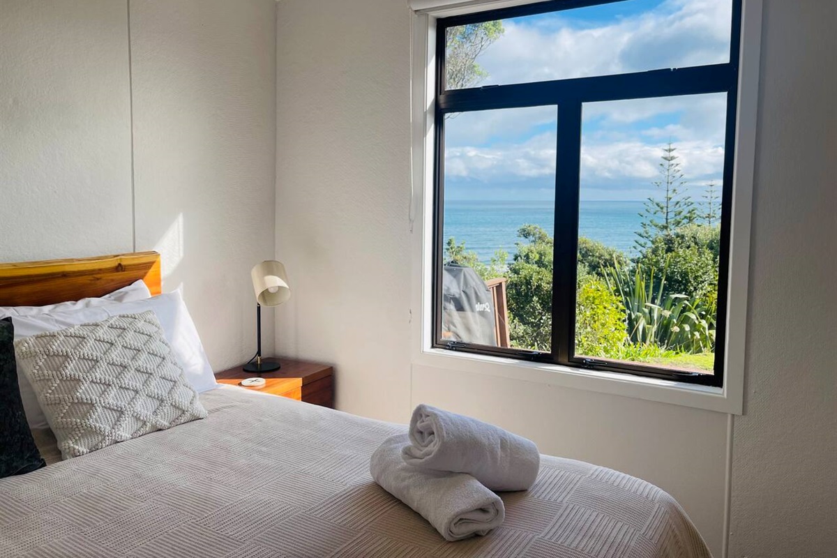 Bedroom 1 has a generous queen bed with a comfy memory foam mattress topper, bedside table lamps for that cozy bedtime read, amazing views out to Kapiti Island, a smart T.V. and an eco heater to keep you warm and snug in winter.