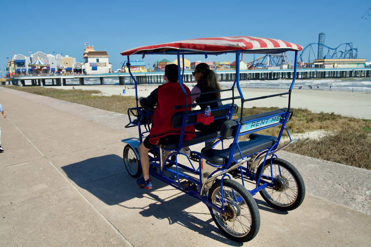 Pedal along the Seawall in a covered family cycle with ocean views and Pleasure Pier in the background. See our Attractions & Things To Do page for info on this and more!